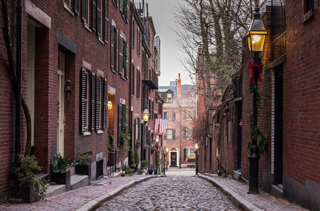 Acorn Street in Beacon Hill: a narrow cobbled lane of brick row houses with black shutters and window boxes.