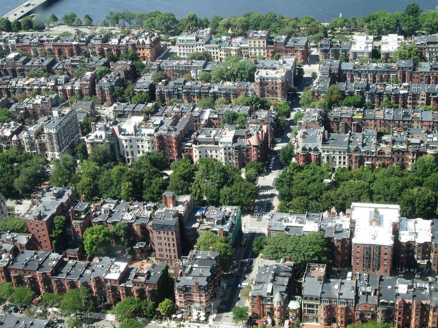 Looking straight down on the rooftops of Back Bay's Victorian row houses and the tree-lined Commonwealth Avenue Mall, with the Charles River and the Esplanade at the top of the frame.