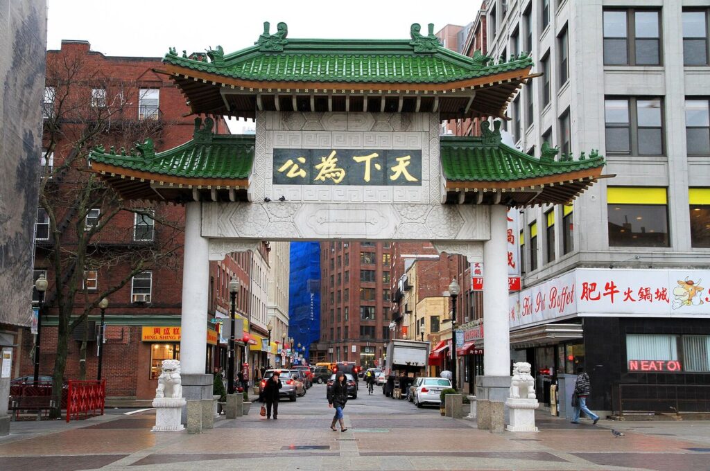 The green-tiled paifang gate at the entrance to Boston's Chinatown, with stone lions at its base.
