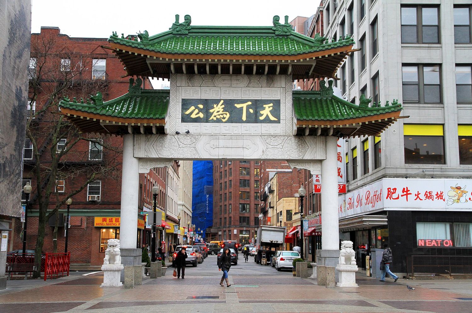 The green-tiled paifang gate at the entrance to Boston's Chinatown, with stone lions at its base.