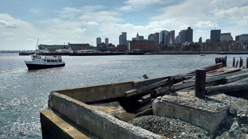 An MBTA harbor ferry crossing Boston Harbor with the downtown skyline behind it.
