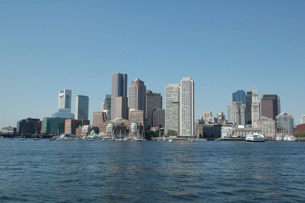 Boston's downtown skyline seen low across the water from Boston Harbor on a clear day.