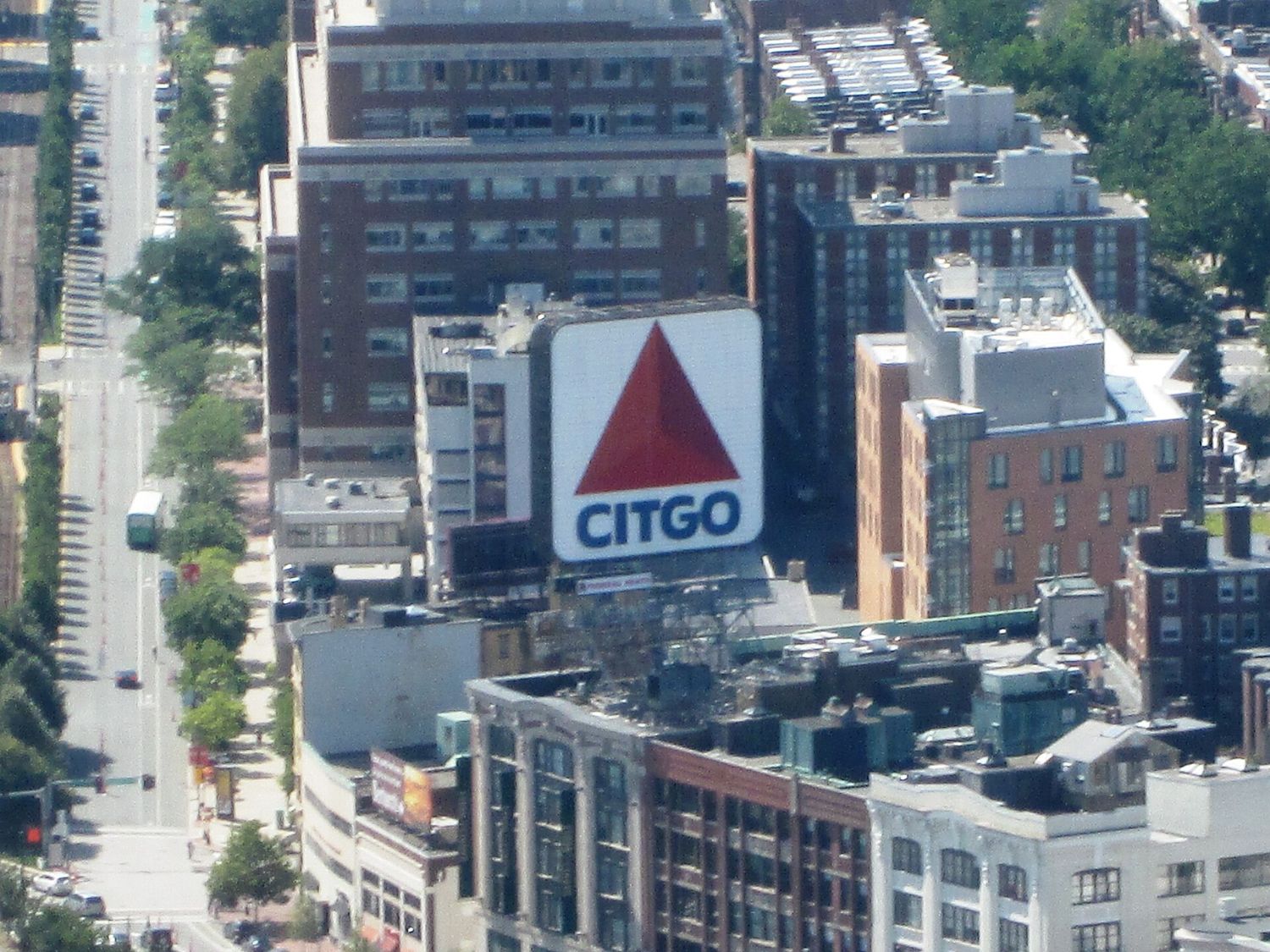 The large illuminated CITGO sign, a red triangle above blue lettering, on a rooftop in Kenmore Square, seen from high above with Commonwealth Avenue running past.
