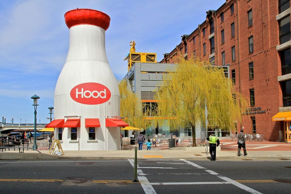 The forty-foot Hood milk bottle standing on Museum Wharf outside the Boston Children's Museum, with the museum building and a willow tree behind it.