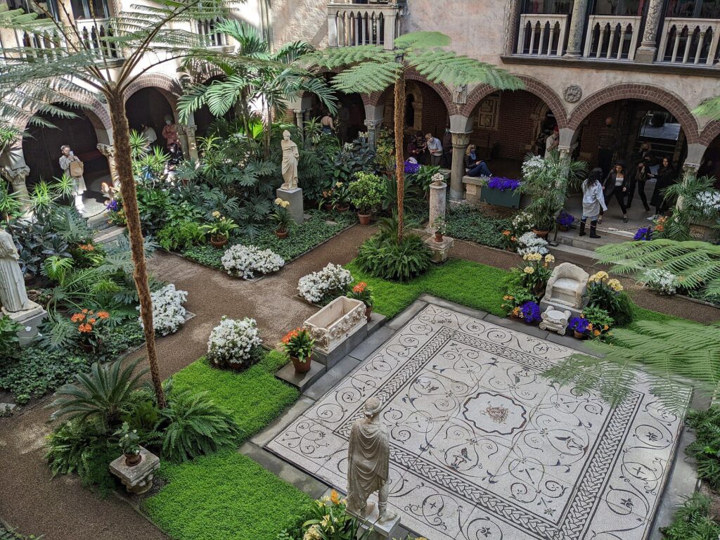 The glass-roofed Venetian courtyard at the Isabella Stewart Gardner Museum, filled with ferns, palms and Roman statuary.