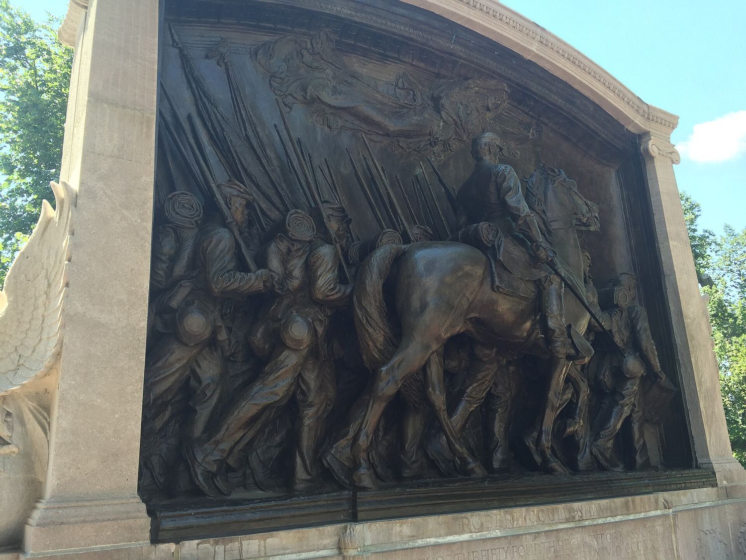 The bronze relief of the Robert Gould Shaw and 54th Massachusetts Regiment Memorial, showing Shaw on horseback beside a column of marching Black infantrymen with rifles on their shoulders and an allegorical figure floating above.