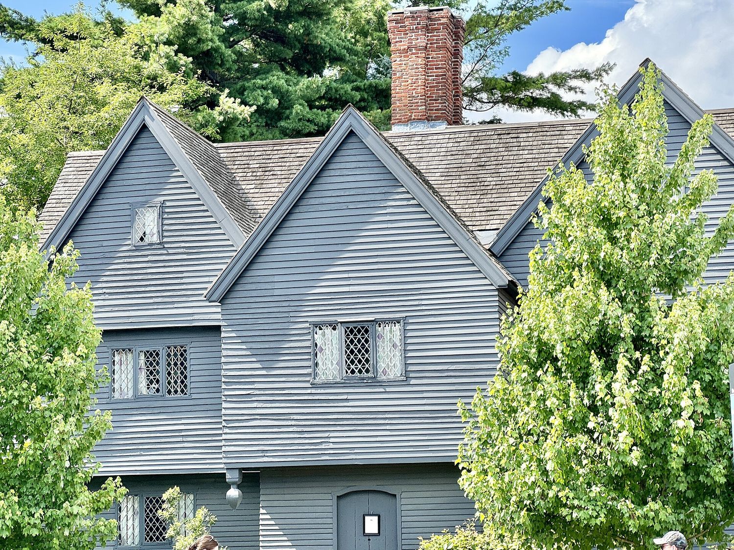 The Witch House in Salem, Massachusetts: a dark gray seventeenth-century timber house with steep gables, diamond-paned windows and a brick chimney.